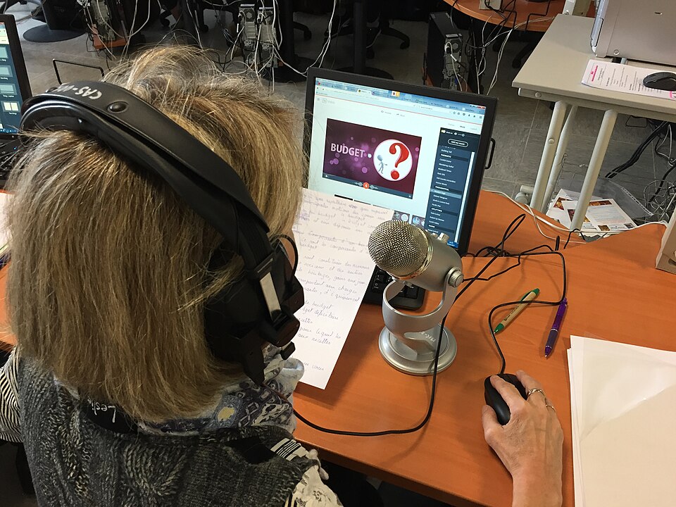 Podcast 主持人戴著耳機，對著桌上的麥克風看稿錄音