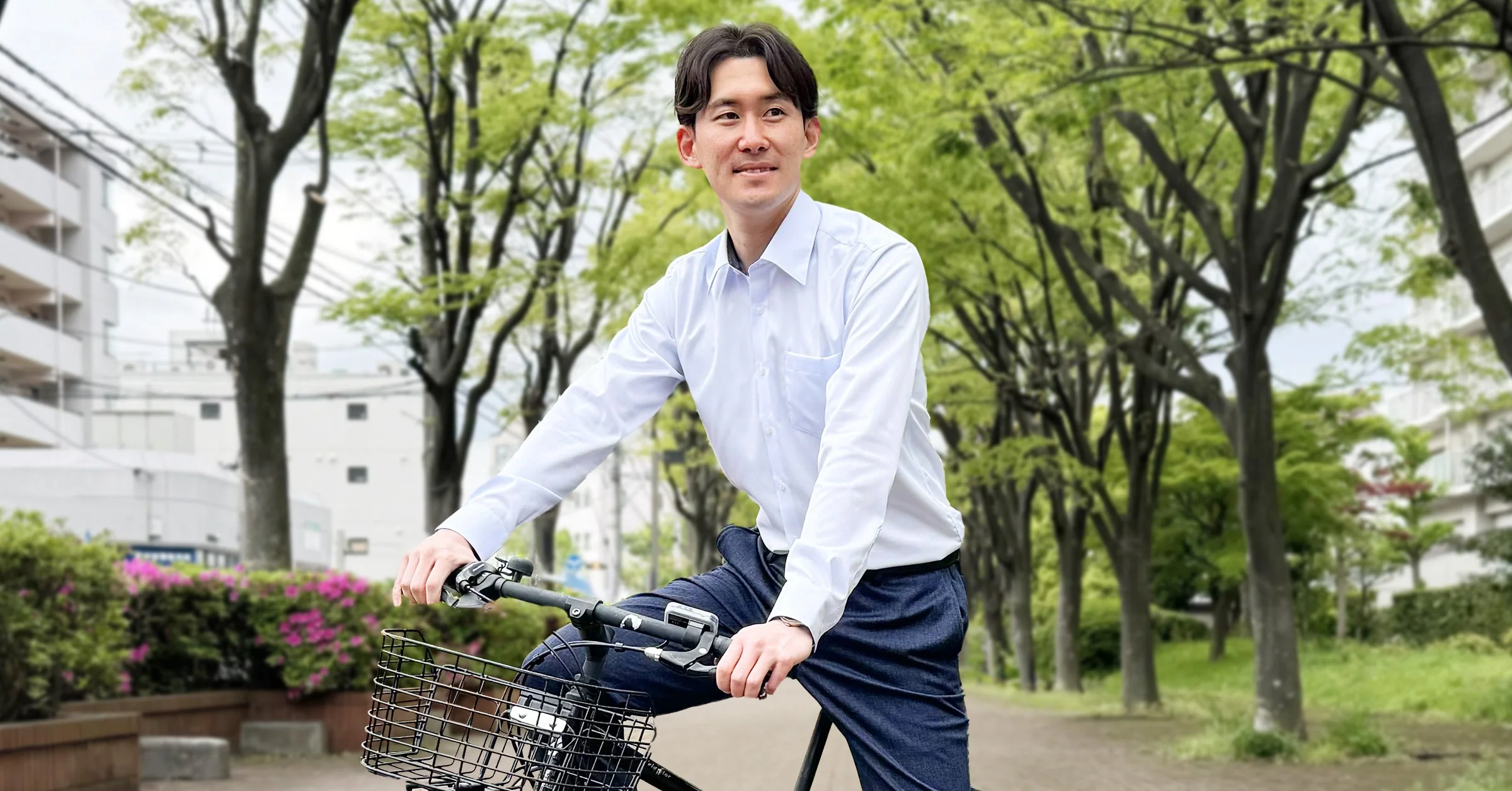亞洲男士穿白色長袖襯衫、深色牛仔褲,坐在自行車上的城市休閒造型