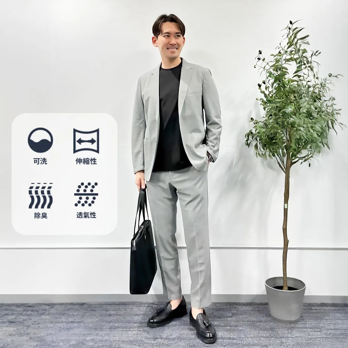 亞洲男士穿灰色西裝外套與長褲、黑色上衣和黑色手提包