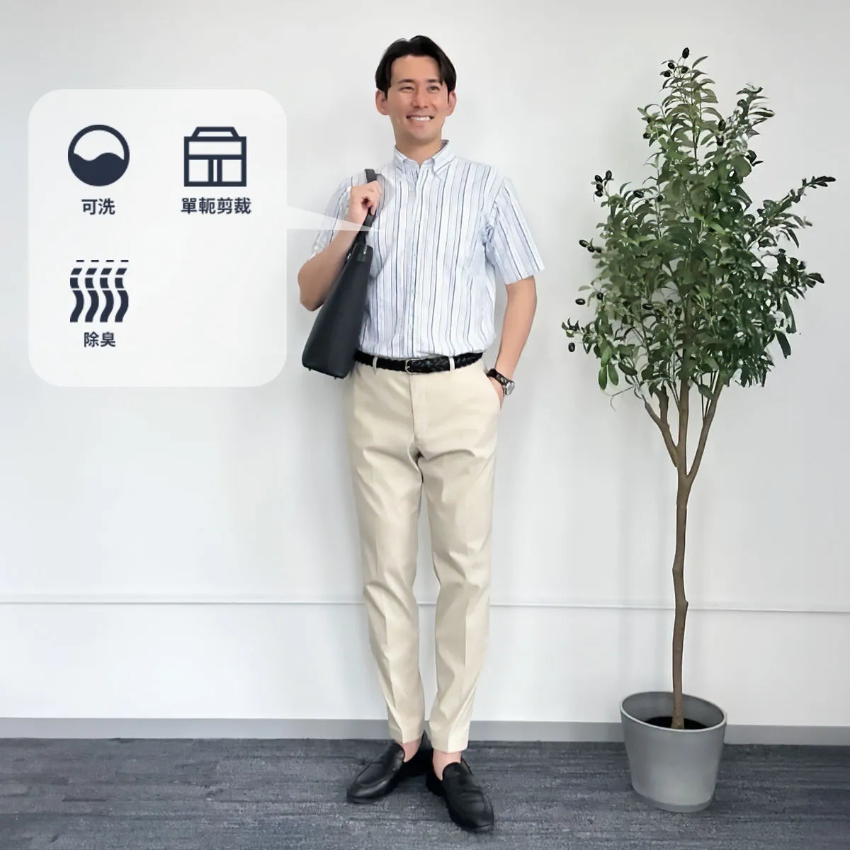 亞洲男士穿細條紋短袖襯衫與米白長褲,肩背黑色通勤包