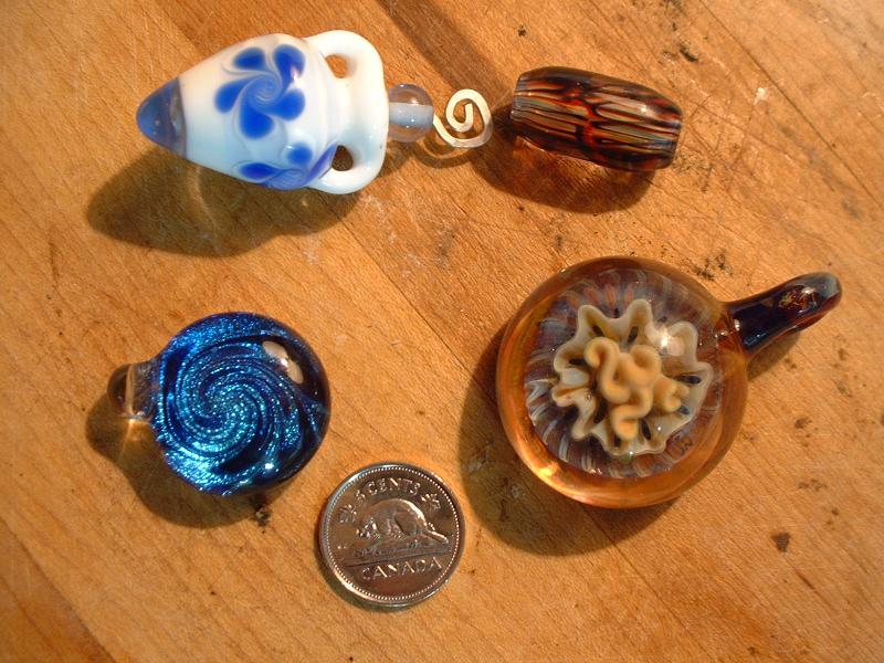 手工吹製玻璃珠與吊墜實物,旁置硬幣作為大小參照