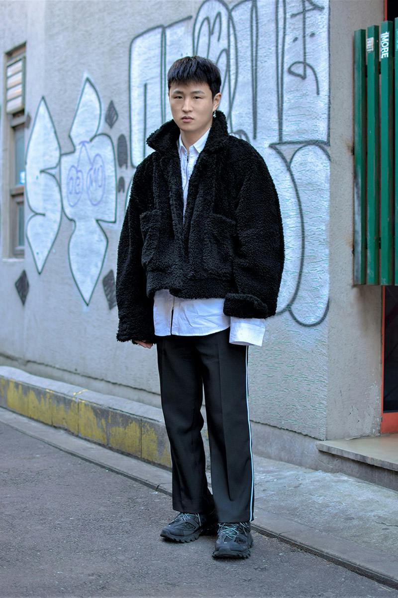 Highsnobiety 首爾冬季街拍：黑色羊羔毛外套、白襯衫與深色長褲呈現乾淨的城市層次