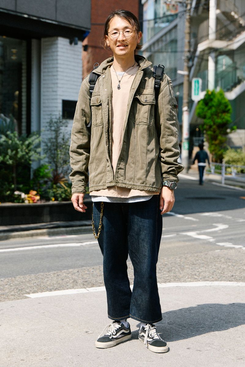 男士穿橄欖色復古外套、米色內搭與深色牛仔褲的日常街拍