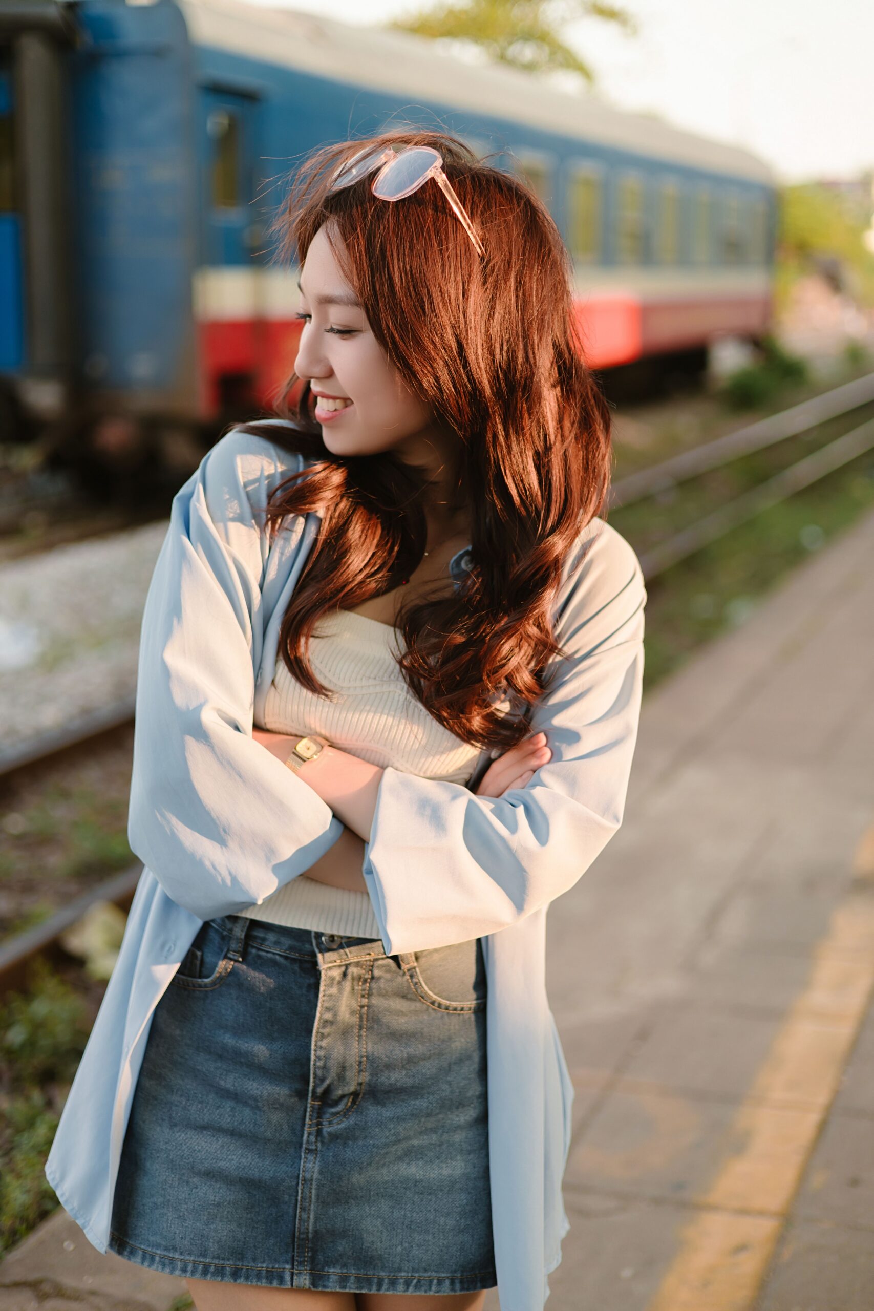 亞洲女性穿淺藍開襟衫、白色羅紋上衣和丹寧短裙的街拍,畫面未拍到鞋子