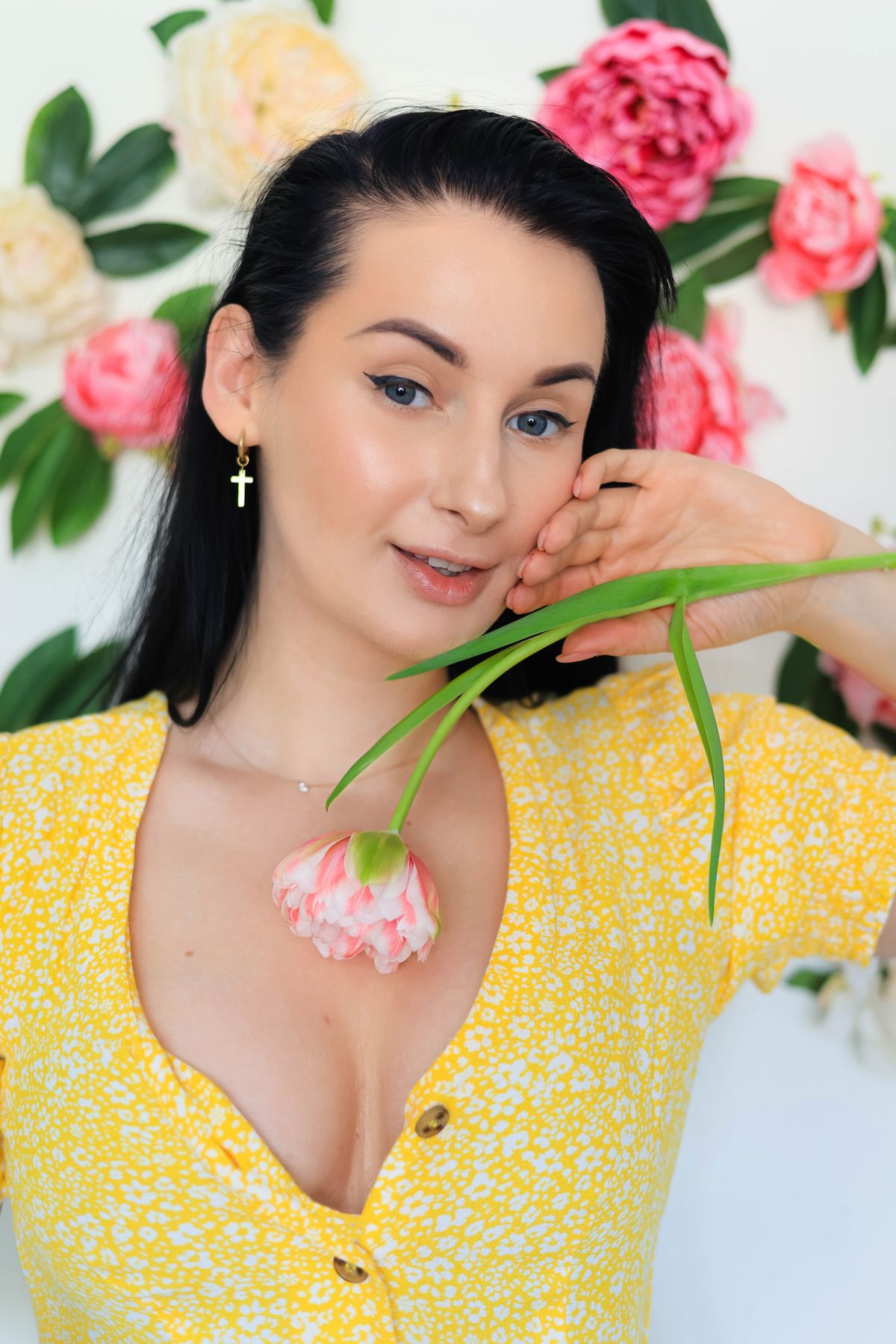 女性穿黃色短袖上衣並置身粉色花景前的近照