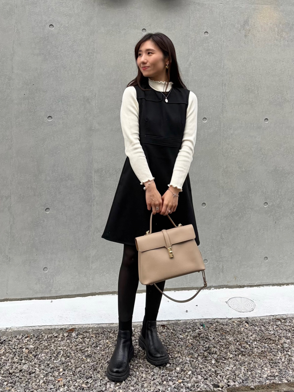 UNIQLO StyleHint 2025 年穿搭:黑色吊帶洋裝疊穿白色荷葉領上衣,搭黑色褲襪、厚底短靴與米色包