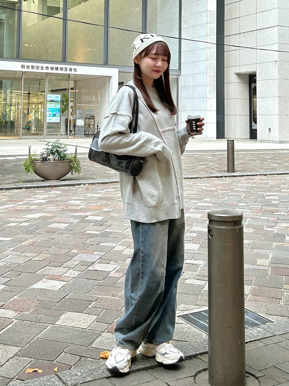 亞洲女性穿灰色寬版圓領衛衣、藍色牛仔褲與厚底白球鞋