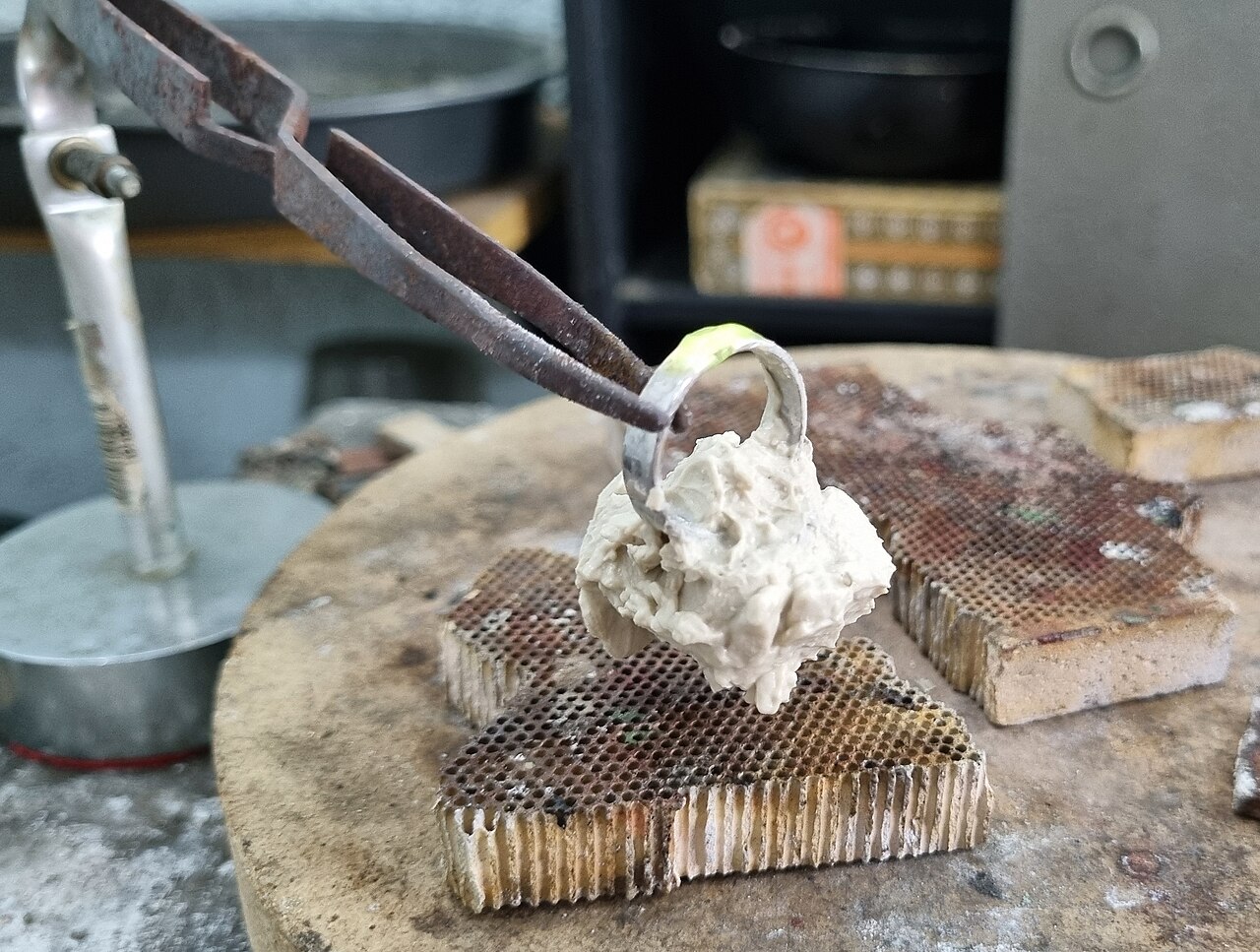 珠寶師在改圍作業中以隔熱膏保護戒指上的寶石