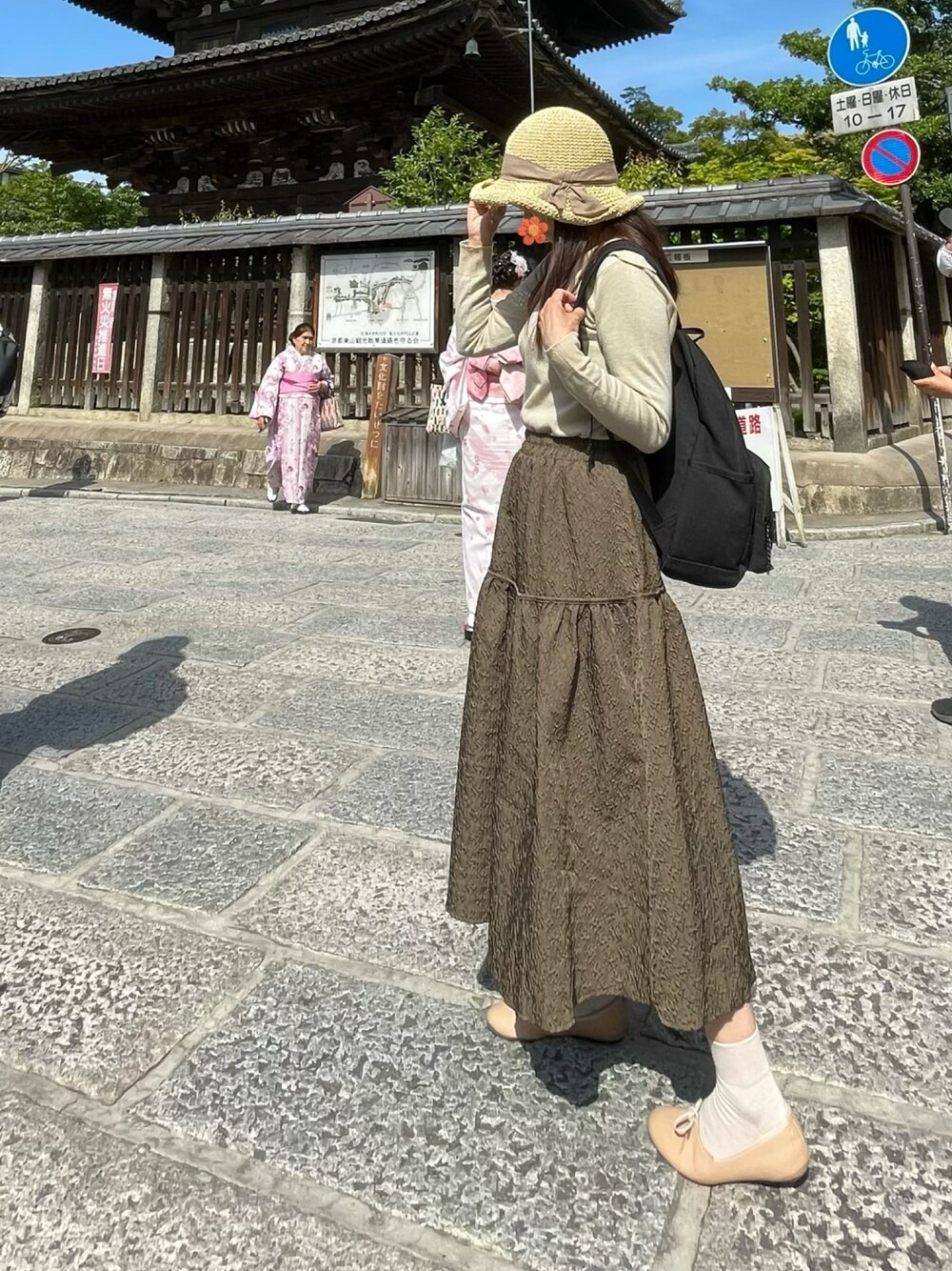 米色上衣、棕色長裙、平底鞋、草編帽和後背包的京都旅行穿搭