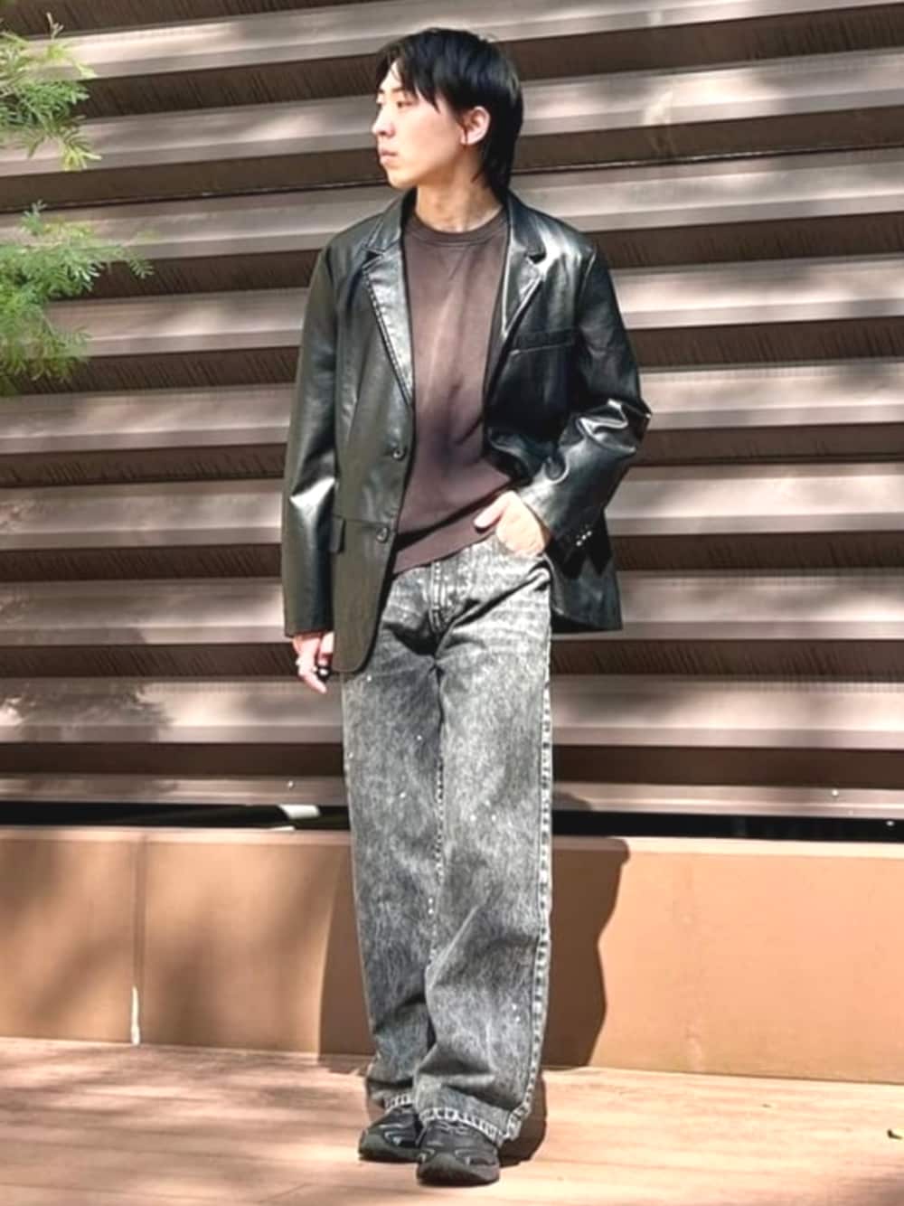 黑色仿皮西裝外套搭棕色上衣和深色丹寧，對照正式駁頭與休閒褲料混搭的效果。