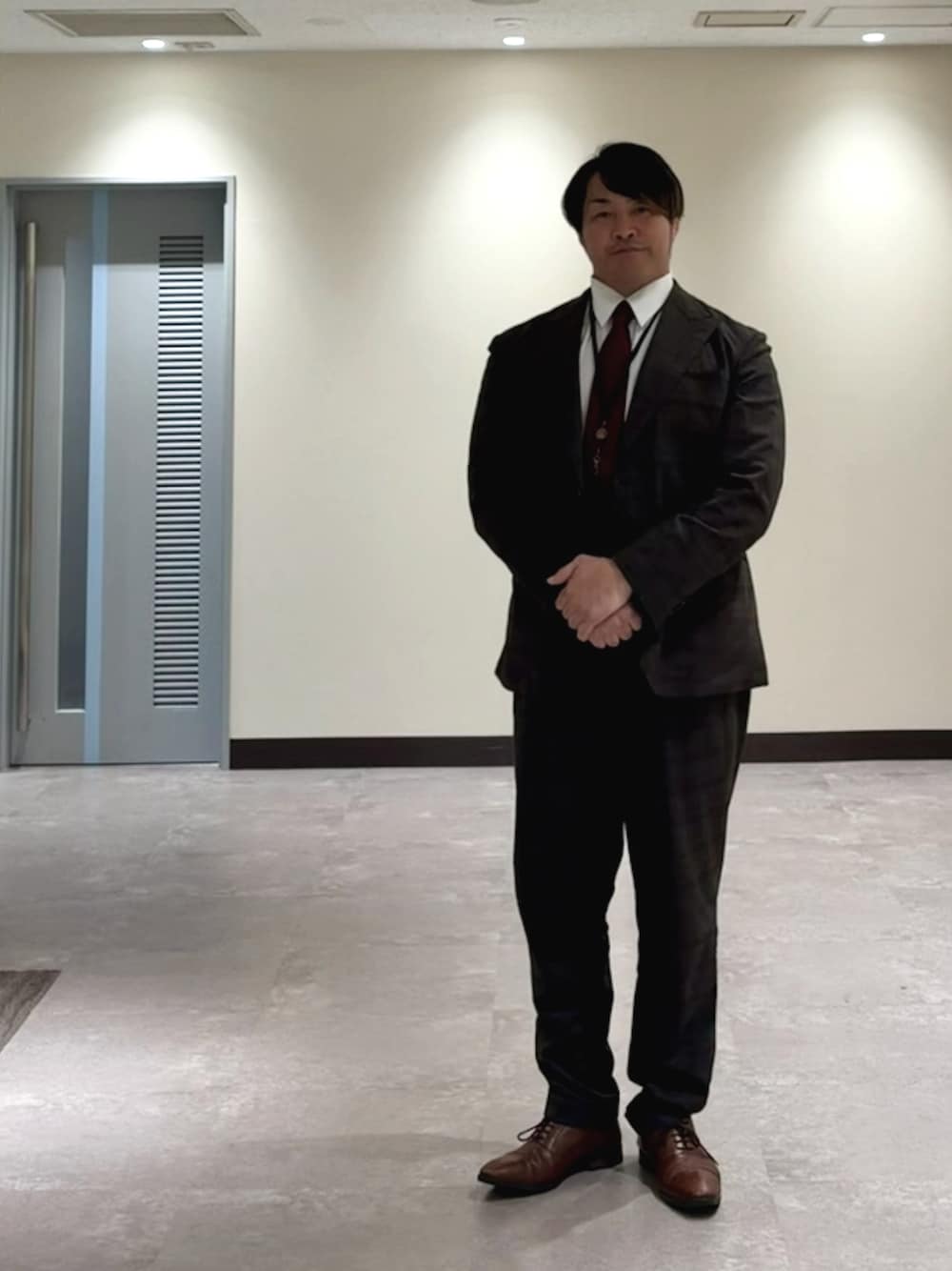男士穿深色成套西裝、白襯衫和酒紅領帶,示範正式面試服裝的整體配色與領口整理