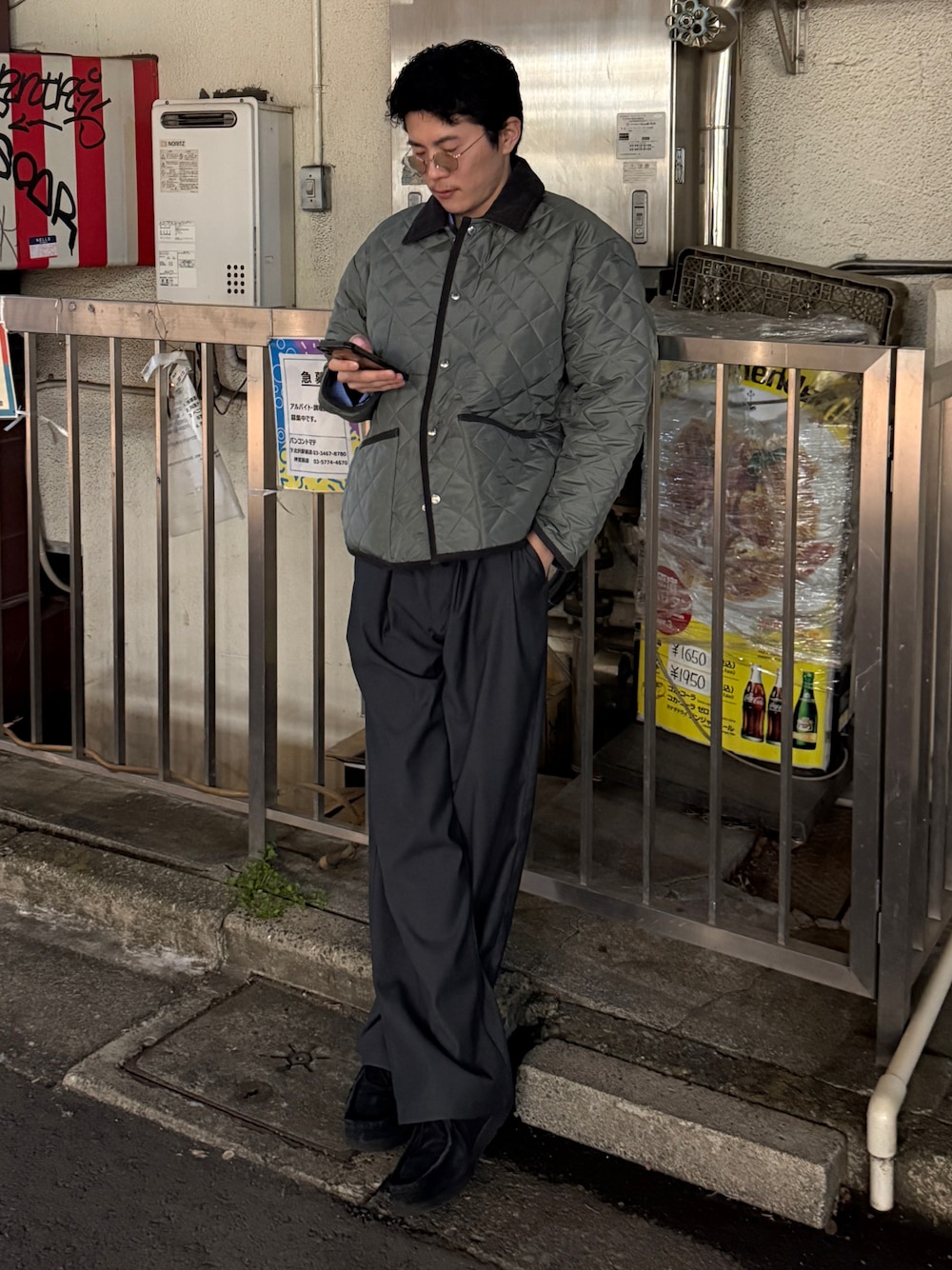 灰綠色短版菱格外套搭配黑色內搭與深色長褲,呈現短外層的下擺位置和深淺配色