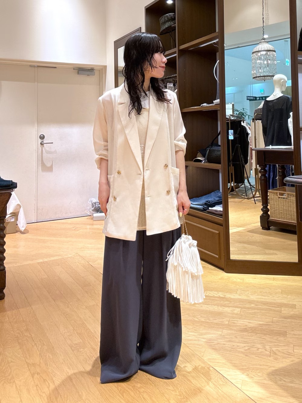 日本女性以白色長版西裝外套、米色內搭、深色寬褲和白色流蘇手提袋組成的日常穿搭