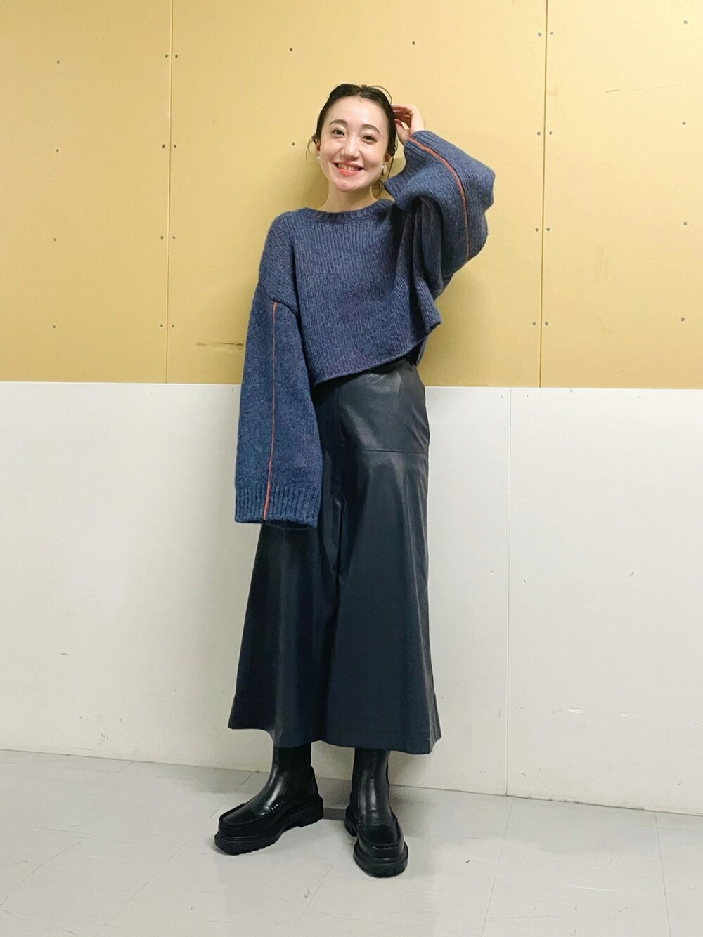 日本 WEAR 實穿:藍色寬鬆短版針織上衣,搭配深色仿皮微 A 字中長裙與黑色側拉鍊靴