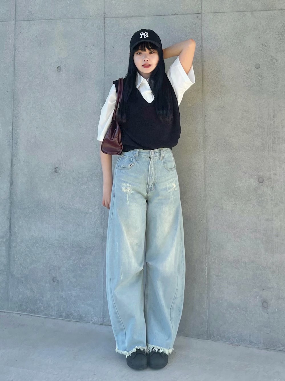日本 WEAR 實穿:白色短袖襯衫外疊黑色針織背心,搭配淺藍超寬牛仔褲、深色球鞋、黑色帽子與酒紅色肩包