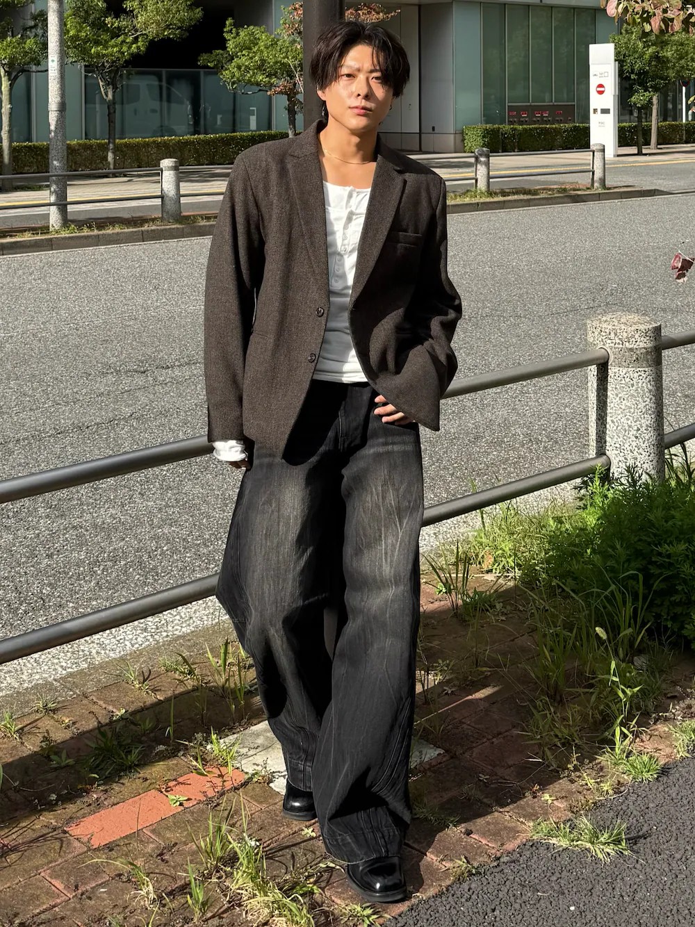 日本男性穿棕灰色人字紋粗花呢西裝外套、白色高針織亨利領、黑色立體寬版丹寧褲與黑色短靴