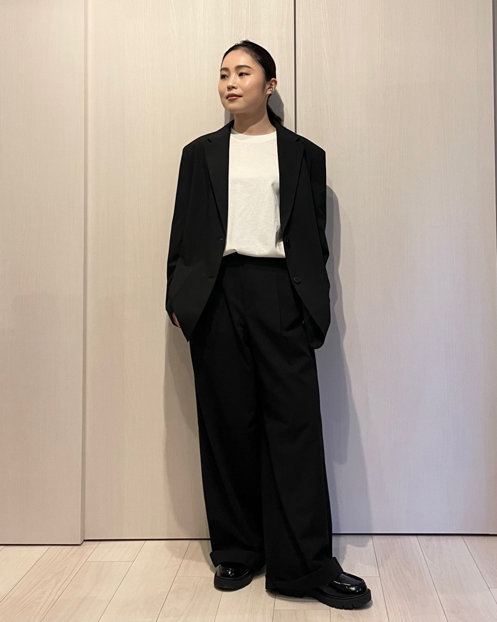 日本女性穿白T、黑色西裝外套、黑色寬褲與黑色樂福鞋