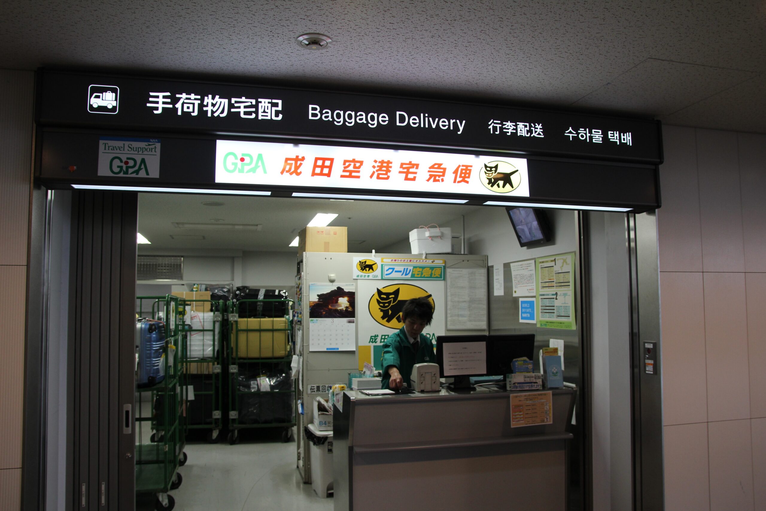 成田機場行李宅配櫃檯，招牌標示 Baggage Delivery 與行李配送